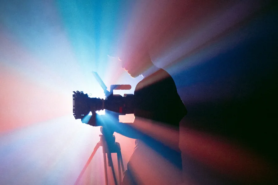 Caméra sur trépied découpée par des faisceaux de lumière colorée